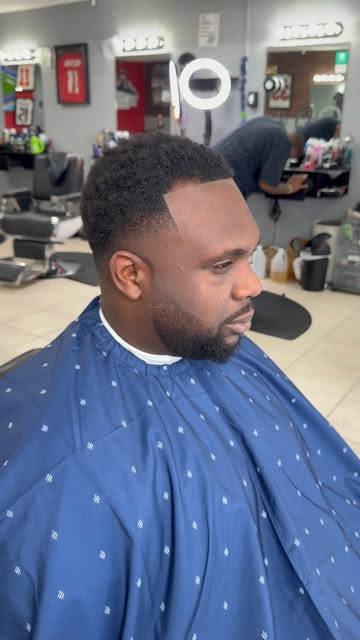Client in a blue cape with a fresh haircut and shaped beard